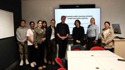 A group of smiling people standing in front of a presentation screen