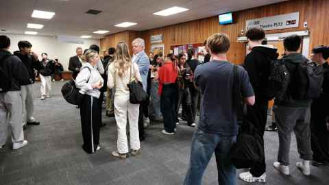 Students mingling with older adults outside a lecture theatre
