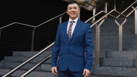 A smiling Asian man wearing a suit