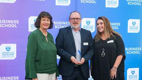 Two smiling women flanking a bearded man.