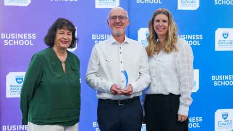 Two smiling women flanking a bearded man.