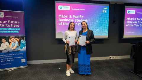 Two women standing in front of a screen that says 'Maori and Pacific Business Student of the year 2024' holding certificates.