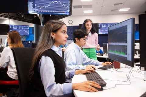 Young people working on computers with graphs on the screens.