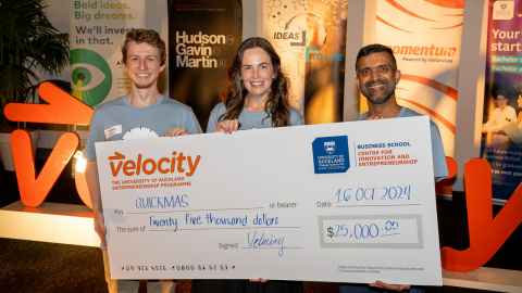 Three students holding a giant $25,000 cheque.