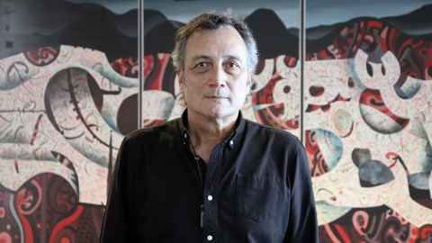 Hone Thorpe, Kaiārahi to the Business School standing in front of an intricate contrasting Māori artwork.