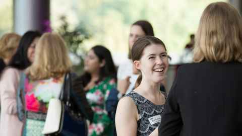 Smiling women in conversation at an event.