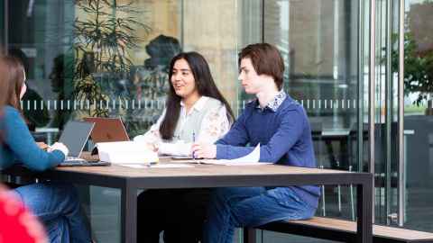 students at a table with laptop, chatting