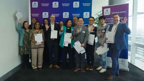 Group of people standing together smiling and holding certificates