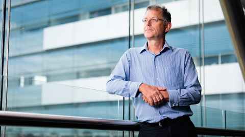 An middle-aged man leaning on a railing inside a building