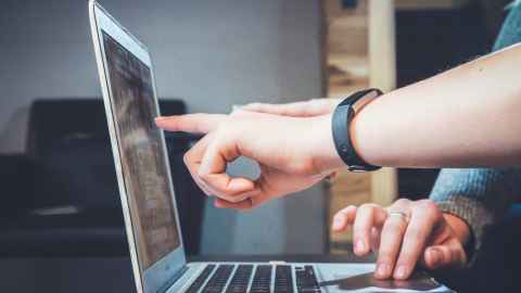 Someone pointing at a laptop screen.