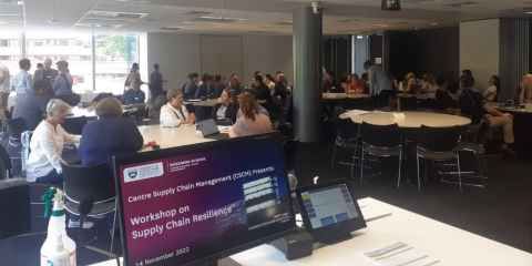 A classroom full of people with the words 'Workshop on supply chain resilience' on a screen on the lectern.