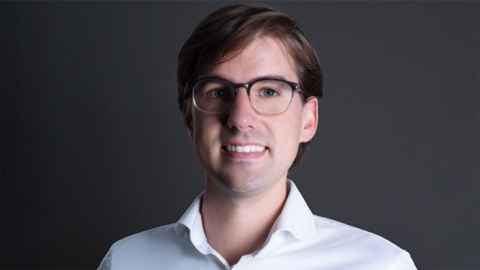 A smiling young man wearing glasses