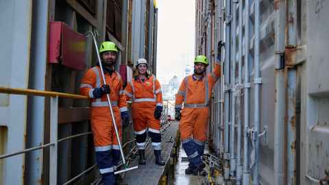 Three workers in hard hats and hi-vis suits