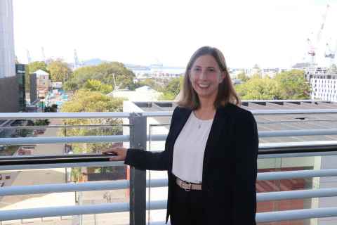 A smiling woman standing on a building balcony