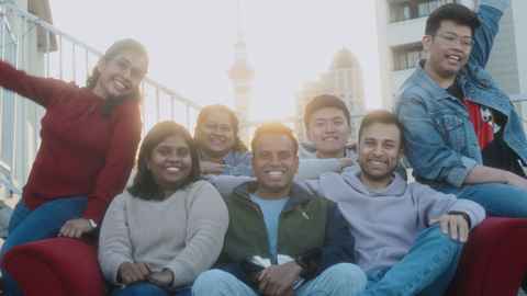A group of PhD students sitting on a read couch outside on a sunny day.
