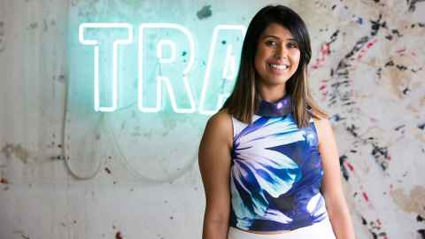 Vanisha Narsey standing in front of TRA neon sign.