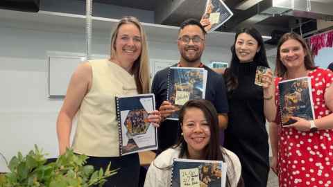 Five smiling MBA graduates hold their A+ final reports