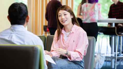 Two postgraduate students seated on couches discussing