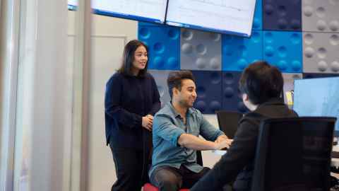 Three students gathered around computer desk
