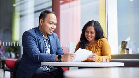 A male and female student looking at a document