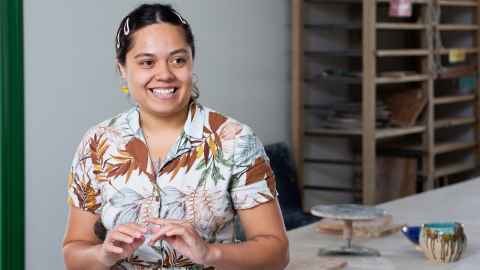 Fine Arts graduate Ashleigh Taupaki smiling in her studio in Auckland