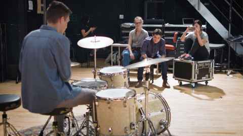 A student plays the drums with friends