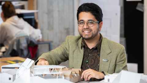 Close up of Sahil smiling with architectural models in front of him on a table