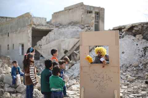 Children watch a puppet show in Syria