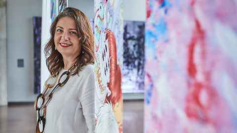 Portrait of Gul Inanc standing in front of art work 