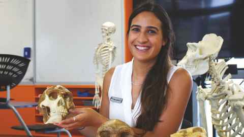 Sina Leilua inside a biology lab holding a model skeleton