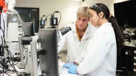 Engineering student looking through microscope