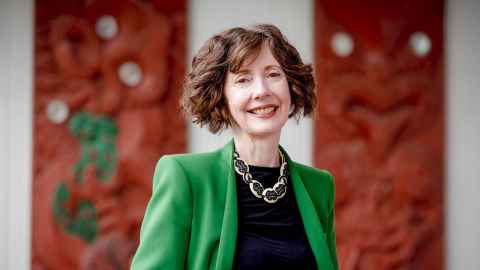 Associate Professor Lee Beattie standing in front of public sign in Wynyard Quarter, Auckland. His arms are outstretched and he is talking with three students, whose backs face the camera.