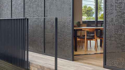 Black building with a wooden deck and metal bannister
