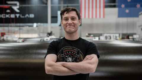 AJ Tyler, Electron Mission Designer at Rocket Lab with his arms crossed and smiling.