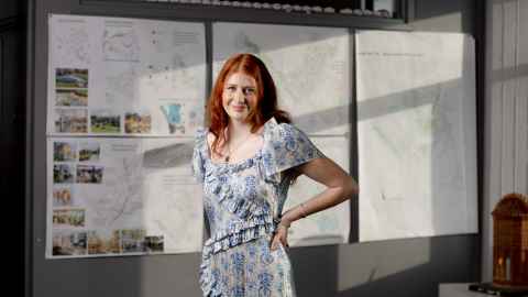 Yasmin stands smiling in front of printed urban planning project