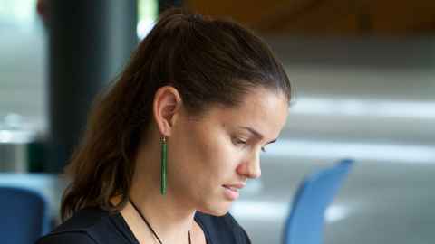 A woman wearing long greenstone earrings.
