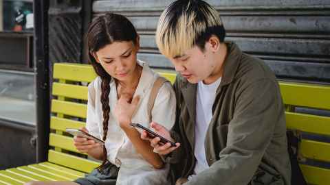 Man and woman looking at a mobile phone while sitting together