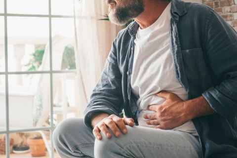 Man sitting with one hand on stomach