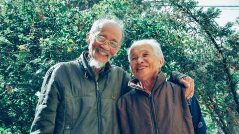 Two elderly people in front of trees.