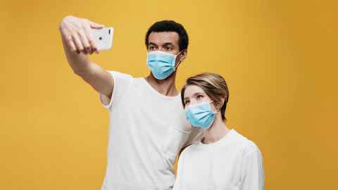 Two people in surgical masks, taking a selfie.