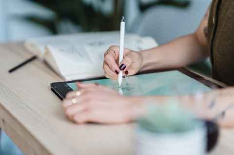 A woman using a tablet, with a book beside her.