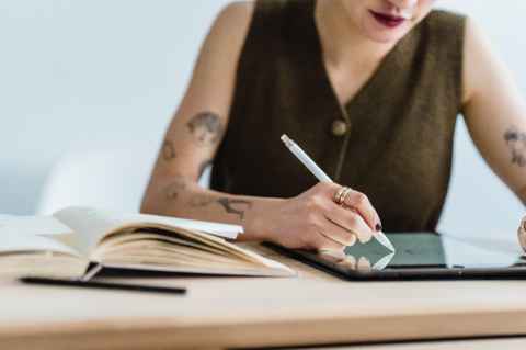 A woman using a tablet, with a book beside her.