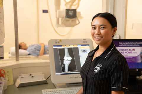Female student sitting next to x-ray image.
