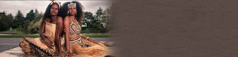 Solomon Islands Pidgin Language Week, two women in traditional dress sitting back to back