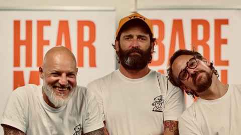 Three men in white t-shirts against a white background covering orange