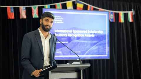Student presenting at the International Sponsored Scholarship Student Recognition Awards. Blue screen in the background. 
