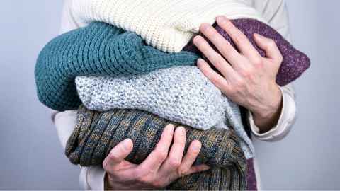 A close up of a person holding woolly jumpers