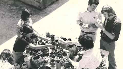 Black and white photograph of people looking at ceramic artifacts.