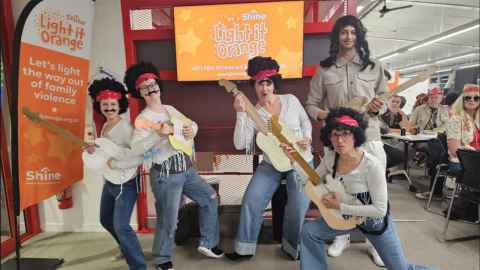 Staff members dressed as 1960's hippies posing with guitars