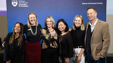 Six members of staff smiling at the camera against a blue background